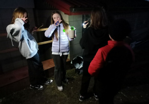 Zadowolone uczennice po wykonaniu zadania podczas podchodów. Jedna z uczennic trzyma w ręku posadzoną roślinę w doniczce.