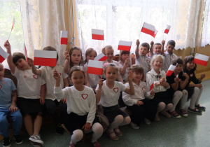 Grupa przedszkolaków z symbolami narodowymi na apelu.