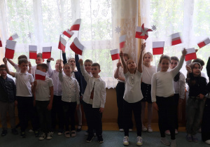 Uczniowie szkoły z flagami na uroczystym apelu.