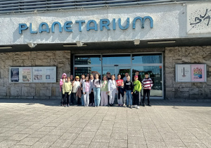 Wejście do Planetarium w Olsztynie. Uczestnicy wycieczki wraz z opiekunem pozują do pamiątkowego zdjęcia.