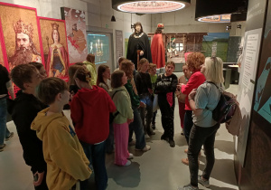 Uczniowie rozpoczynają zwiedzanie Muzeum w Grunwaldzie.. W tle widnieją postacie króla Władysława Jagiełły oraz jego brata, Wielkiego Księcia Litewskiego Witolda. Po lewej stronie widnieją portrety króla Kazimierza Wielkiego oraz królowej Jadwigi Andegaweńskiej.