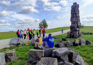 Uczniowie podążają wybrukowanym szlakiem na pole bitwy pod Grunwaldem. Wokół rozciągają sie malownicze tereny zielone. Po lewej stronie szlaku leżą symbolicznie porozrzucane kamienie, pochodzące z pomnika Grunwaldzkiego w Krakowie.