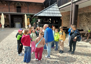 Dziedziniec zamku w Nidzicy. Przewodnik opowiada uczestnikom wycieczki o historii warowni oraz jej architektonicznych walorach.