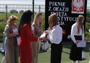 Zadowolona pani dyrektor rozdaje nagrody uczniom teatru ,,Carpe diem”.