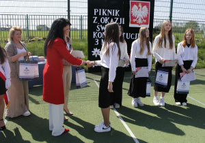 Zadowolona pani dyrektor rozdaje nagrody uczniom teatru ,,Carpe diem”.