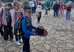Uczeń rzuca kowbojskim kapeluszem do celu.