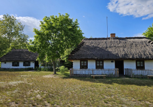 Dwie białe i pokryte strzechą chaty.