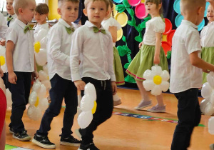 Chłopcy trzymają w ręku balonowe stokrotki.