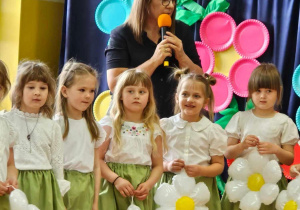 Dziewczynki z balonowymi stokrotkami za którymi stoi ciocia Kasia.