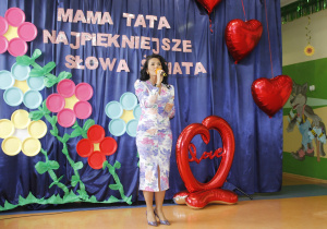 Pani Dyrektor na tle dekoracji z okazji Dnia Mamy i Taty.
