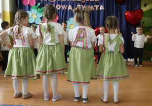 Cztery dziewczynki odwrócone tyłem z literkami przyklejonymi do pleców tworzących wyraz mama.