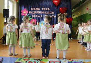 Chłopiec i trzy dziewczynki odwrócone tyłem z literkami przymocowanymi do pleców tworząc wyraz tata.