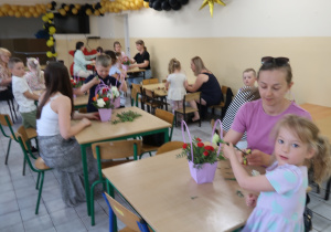 "Kropeczki" i mamy wykonują kompozycję kwiatową.