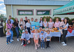 Grupa Pszczółki z wychowawcą i rodzicami przy stoisku ze zdrową żywnością.