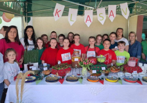 Uczniowie klasy 5 i grupa rodziców przy stoisku przygotowanym na festyn.