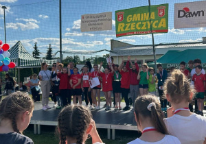 Uczniowie klasy 5 na scenie po otrzymaniu vouchera podarunkowego za zajęcie 1 miejsca.