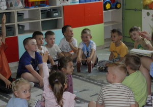 Uczennica z klasy VI a po przeczytaniu wiersza Jana Brzechwy ,,Na straganie” przedszkolakom z grupy ,,Misie” rozmawia z dziećmi na temat wiersza. Przedszkolaki siedzą na dywanie.