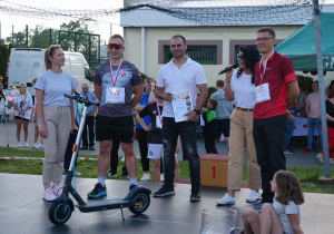 Zwycięzca hulajnogi elektrycznej odbiera swoją wygraną.