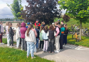 Policjant omawia zasady egzaminu na kartę rowerową uczniom.