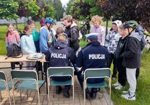 Policjanci podpisują arkusze zaliczeń uczniów ubiegających się o kartę rowerową.