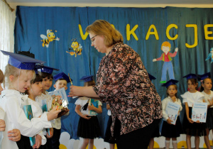Rodzice wręczają dzieciom puchary ukończenia przedszkola.