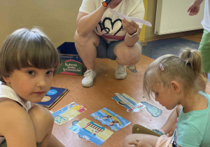 Nauczycielka przekazuje informacje jak bezpiecznie spędzać czas nad wodą, dzieci oglądają muszelki.