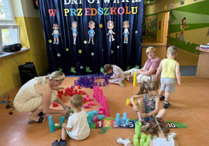Dzieci wraz z rodzicami bawią się piaskiem kinetycznym.