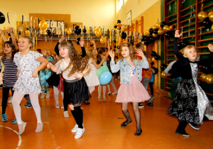 zdjęcie ukazuje grupkę tańczących dzieci z rękoma w górze