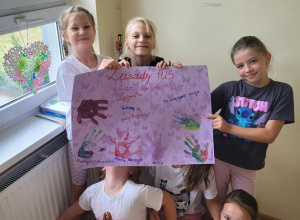 Uczennice pokazują plakat z zasadami.