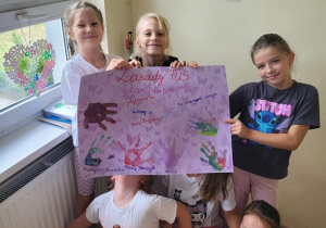 Uczennice pokazują plakat z zasadami.