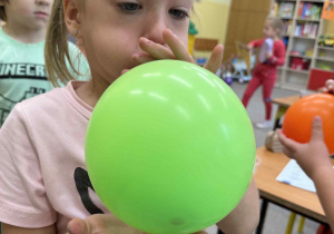 Dziewczynka dmucha zielony balonik.