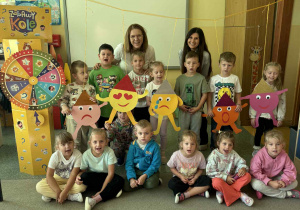 Grupowe zdjęcie dzieci z grupy Żabki z Panią psycholog, wychowawcą oraz emotikonami.