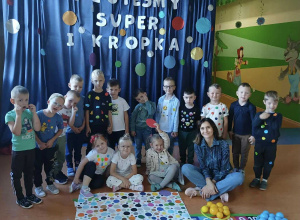 Zdjęcie grupowe dzieci z grupy Promyczki na tle napisu Jestem super i kropka.