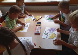 Dzieci z grupy Skoczki wyklejają plasteliną owoce.