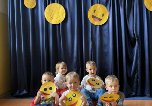 Dzieci z grupy Kamyczki siedzą na czerwonej poduszce z emotikonami.