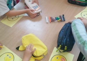 Dzieci z grupy Skoczki malują emotikona.