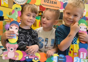 Trzej chłopcy pozują do zdjęcia trzymając fotobutkę z okazji Dnia Przedszkolaka.