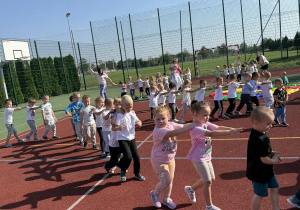 Zabawa "Radosna podróż pociągiem" na boisku w Dniu Przedszkolaka.