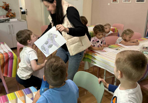 Ciocia Marzenka pokazuje dzieciom swoją krówkę narysowaną do konkursu w Fabryce Krówek.
