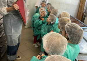 Pani przewodnik pokazuje dzieciom taflę, z której powstają małe cukierki krówki.