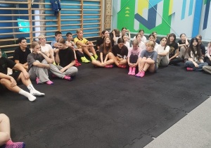 Uczniowie klas 7a oraz 8a w parku trampolin, słuchający instruktora.