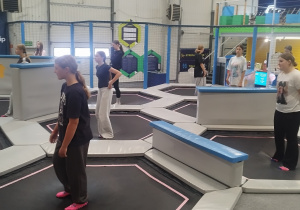 Uczniowie klasy 8a wesoło skaczący na trampolinach w sportowych strojach.