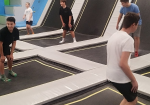 Uczniowie klasy 7a oraz 8a wesoło skaczący na trampolinach w sportowych strojach.