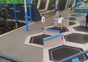 Uczniowie klasy 8a wesoło skaczący na trampolinach w sportowych strojach.