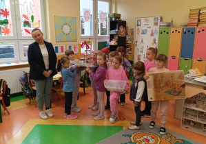Dziewczynki z grupy Skoczki z przedstawicielem rodziców trzymają prezent dla swoich kolegów.