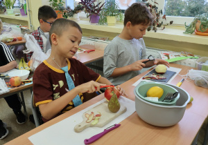 Chłopcy z klasy drugiej podczas wykonywania zdrowej sałatki owocowej.