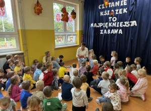 Pani Karolina Tomasik czyta książkę dzieciom z grupy Kamyczki, Szkraby i Promyczki w Dniu Głośnego Czytania.