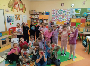 Zdjęcie grupowe dzieci z grupy Skoczki trzymają w dłoniach jabłko.