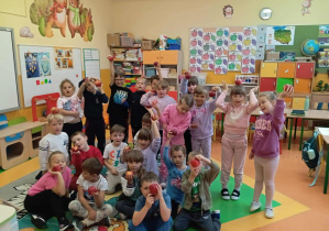 Zdjęcie grupowe dzieci z grupy Skoczki trzymają w dłoniach jabłko.
