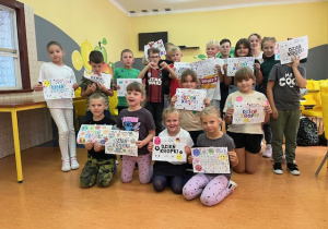 Grupa uczniów przebywających na świetlicy prezentująca prace z Okazji Międzynarodowego Dnia Kropki.